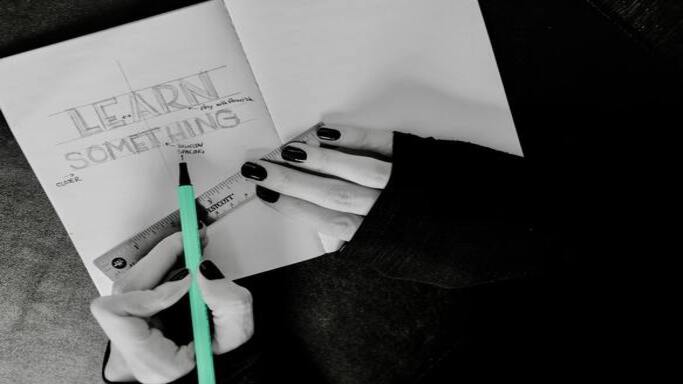 vinette avec un cahier avec le texte 'learn something' et un stylo, symboles de l'apprentissage et de l'acquisition de compétences.